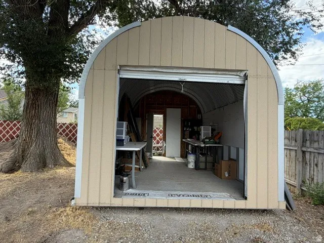Arch-style outbuilding with a roll-up door, corrugated metal interior, and exterior siding