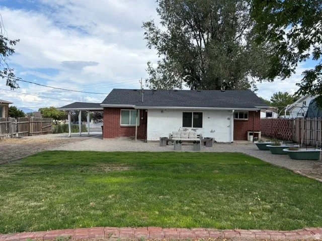 Expansive backyard featuring a manicured lawn, gravel patio, and a carport structure
