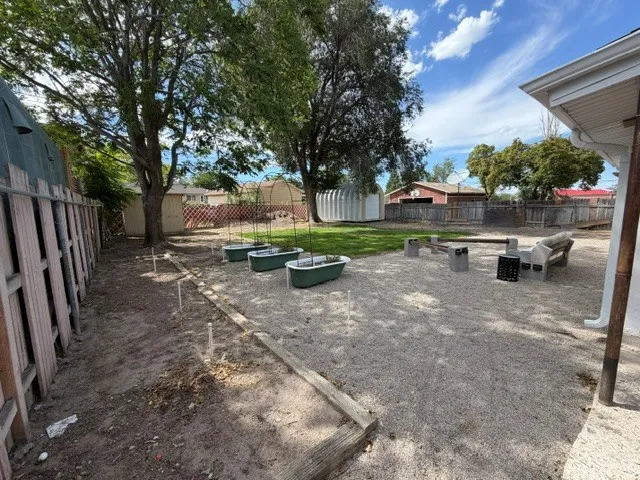 Expansive backyard featuring a gravel patio, mature trees, and a wooden fence