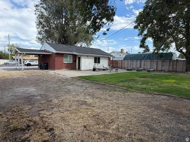 Exterior featuring brick and white siding, an attached carport, and a private rear yard with a fenced perimeter