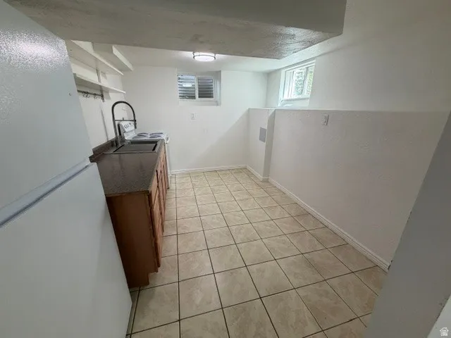 Kitchenette featuring a stainless steel sink, a compact electric range, light wood cabinetry, and tiled flooring