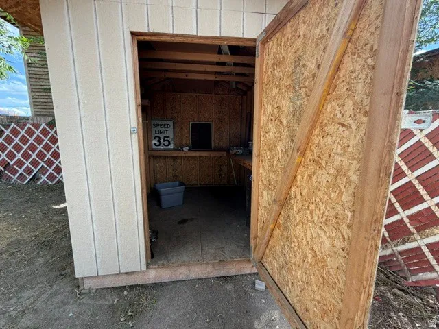 Freestanding utility shed with light-toned siding and an exposed wood interior