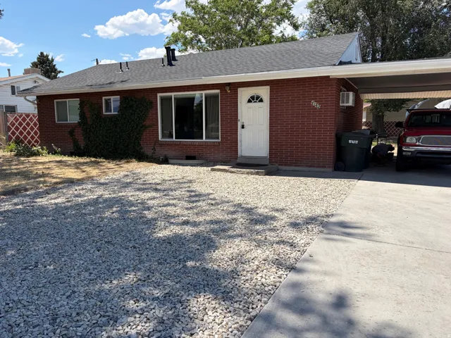 Red brick exterior with white trim, a covered carport, and a white entry door