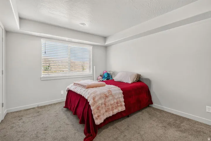 Bright room featuring a large window with horizontal blinds, neutral wall paint, and gray carpet flooring