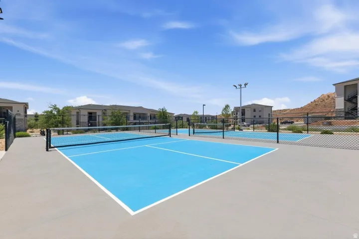 Recreational courts featuring blue playing surfaces, perimeter fencing, and overhead lighting
