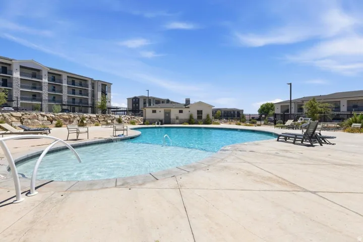 Resort-style swimming pool featuring a curved concrete deck, integrated water features, and expansive sundeck areas