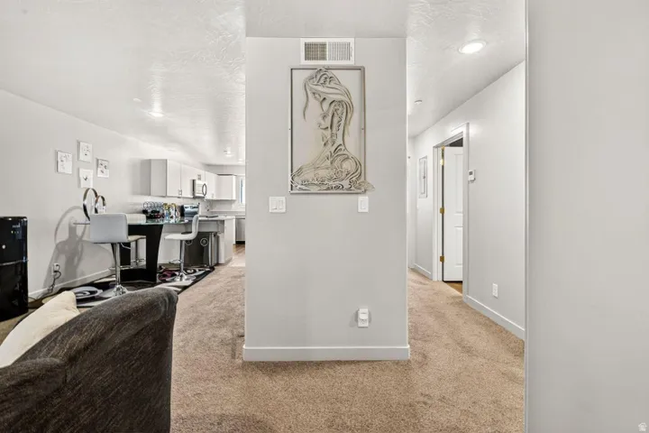 Open concept living space featuring recessed lighting, a modern kitchen with white cabinetry and stainless steel appliances, and contrasting light gray walls