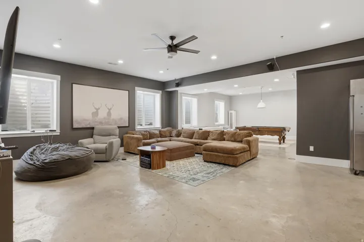 Spacious open-concept lower level with concrete flooring, recessed lighting, and a ceiling fan