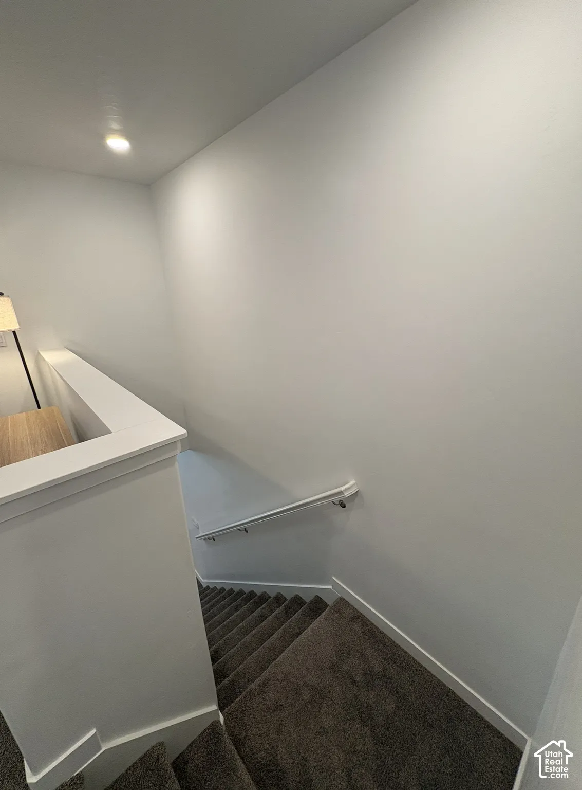 Staircase featuring dark gray carpeting and white handrails
