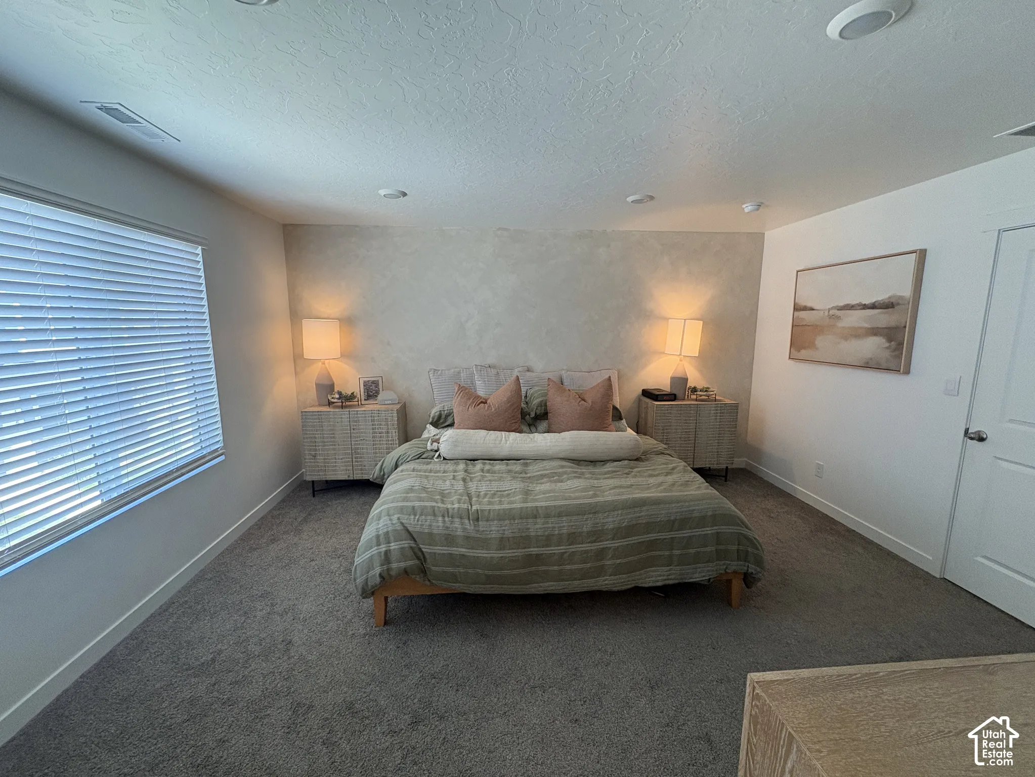 Carpeted room featuring a window with blinds, recessed ceiling lighting, and a textured accent wall