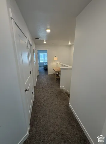 Carpeted hallway featuring white walls, multiple interior doors, and recessed lighting