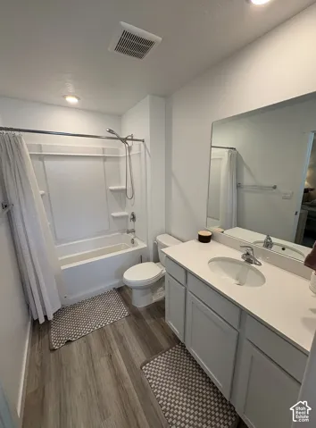 Bathroom featuring a white vanity with an integrated sink, a rectangular mirror, and wood-finish flooring