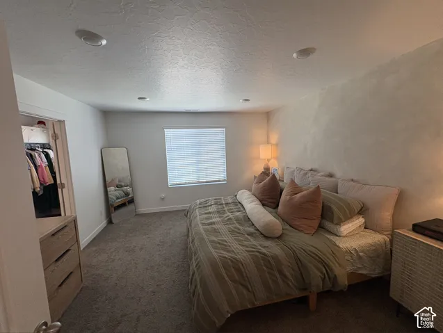 Carpeted bedroom featuring a large window with blinds, recessed ceiling lighting, and a closet with bifold doors