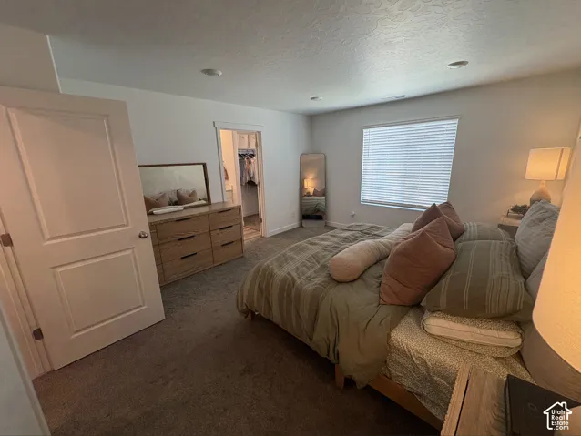 Carpeted interior space featuring a window with blinds, recessed lighting, and a doorway leading to a walk-in closet