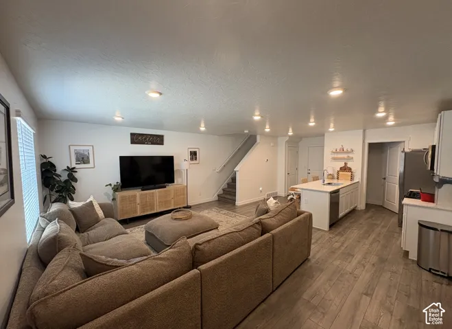 Open-concept living space featuring wood-finish flooring, recessed lighting, and white walls