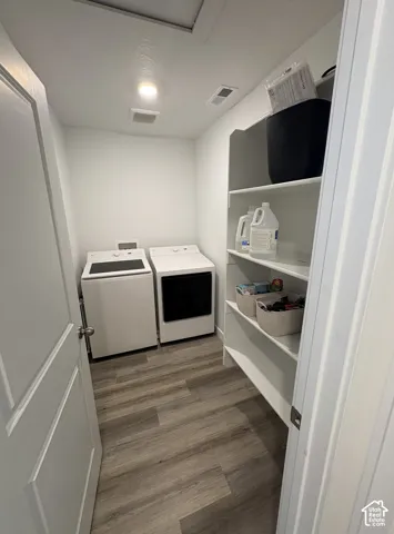 Dedicated laundry area featuring wood-finish flooring, recessed lighting, and built-in shelving