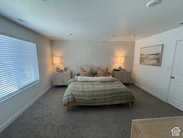 Carpeted room featuring a window with blinds, recessed ceiling lighting, and a textured accent wall