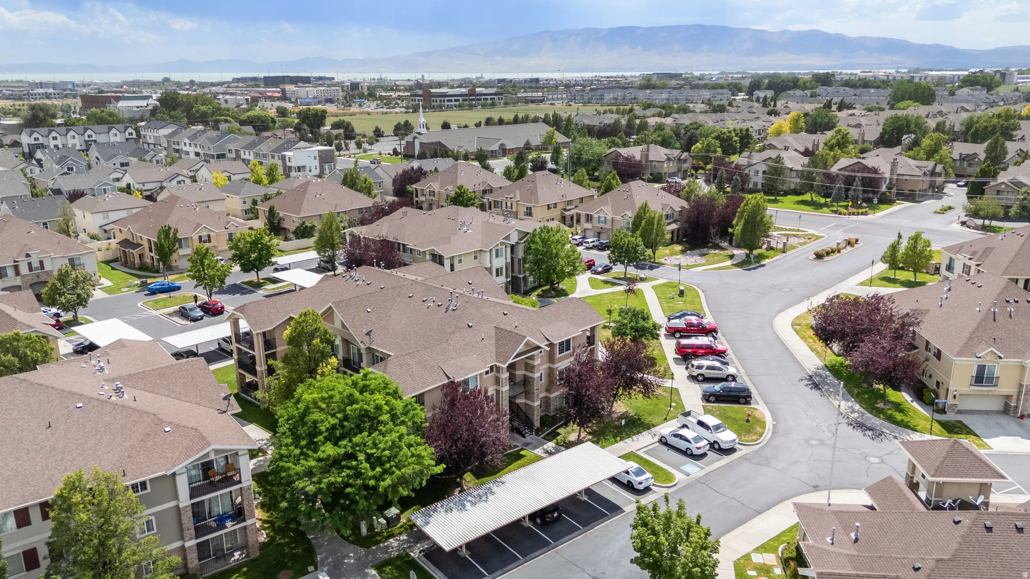 Residential community featuring multi-story buildings and single-family homes, mature trees, paved streets, and covered parking structures