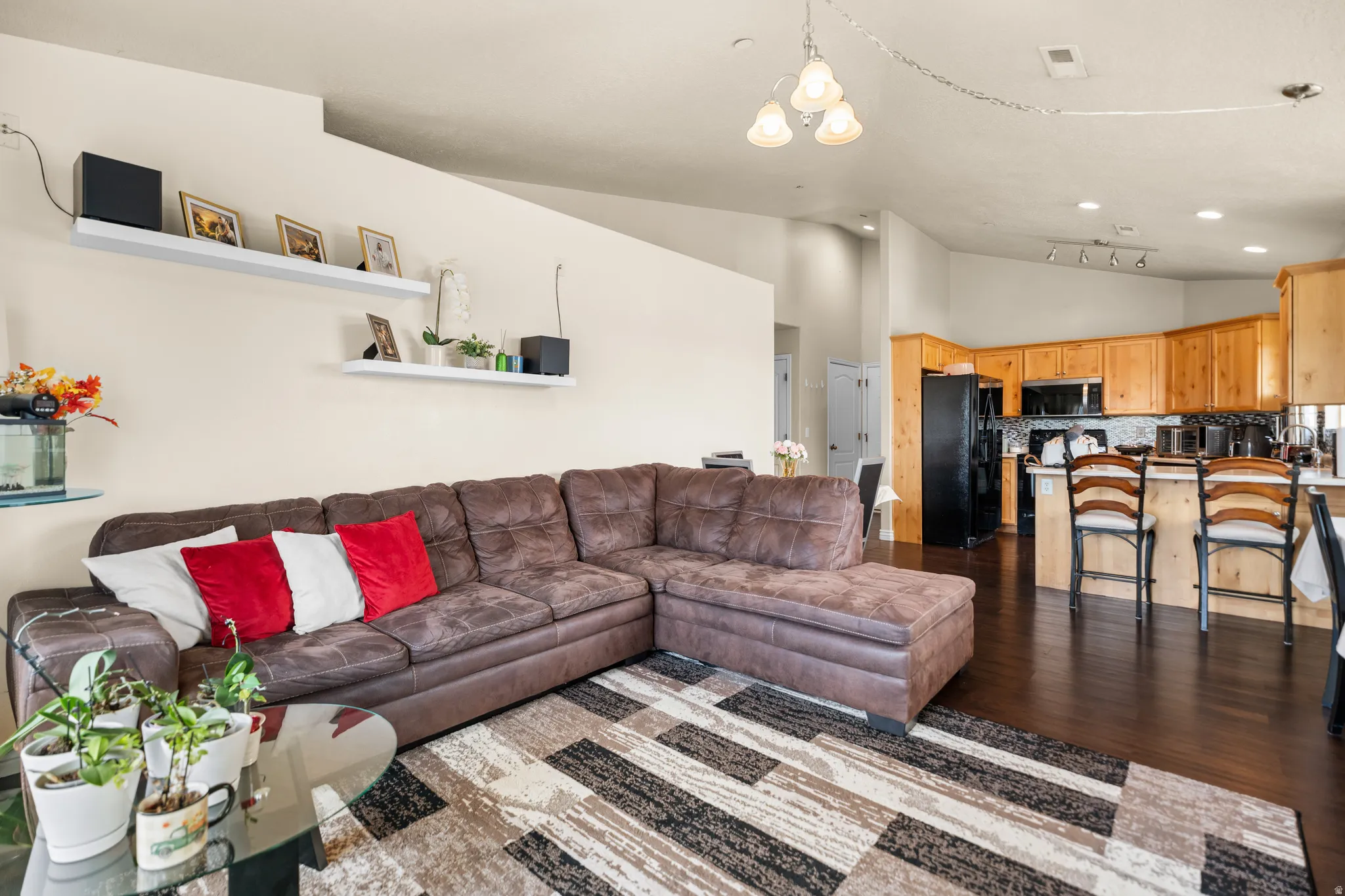 Open-concept living area with dark wood-finish flooring, recessed lighting, and a white floating shelf system