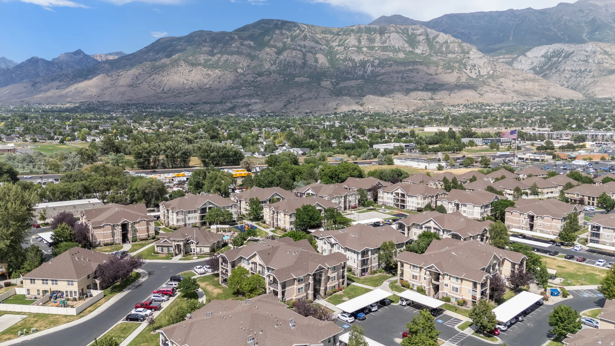 Extensive residential community featuring multiple multi-story buildings with pitched roofs, covered parking areas, and mature landscaping