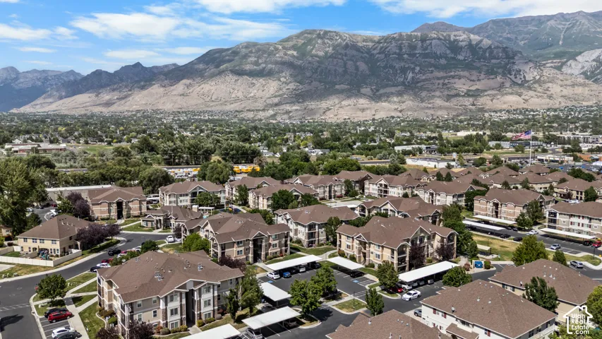 Expansive residential development with numerous multi-story buildings, consistent architectural design, covered parking structures, mature trees, and mountainous scenery