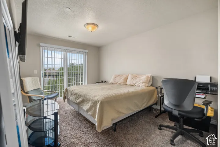 Carpeted room featuring a ceiling-mounted light fixture, light-toned walls, and a sliding glass door with vertical blinds