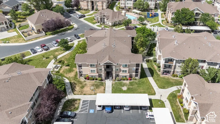 Multi-level apartment building featuring a neutral-toned exterior, gabled roofline, covered parking, and an on-site swimming pool