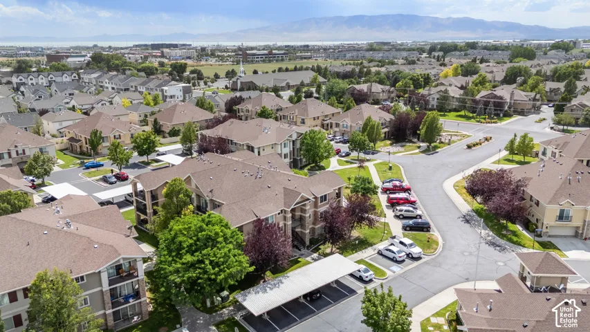 Residential community featuring multi-story buildings and single-family homes, mature trees, paved streets, and covered parking structures