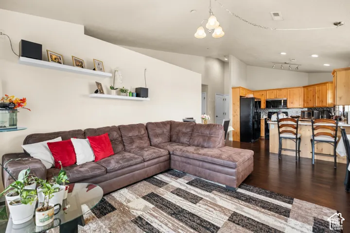 Open-concept living area with dark wood-finish flooring, recessed lighting, and a white floating shelf system