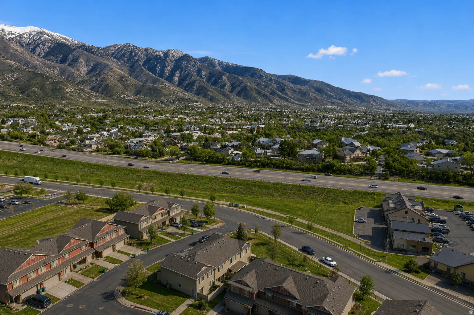 Aerial perspective showcasing a residential area with townhomes and apartment buildings, framed by a prominent mountain range