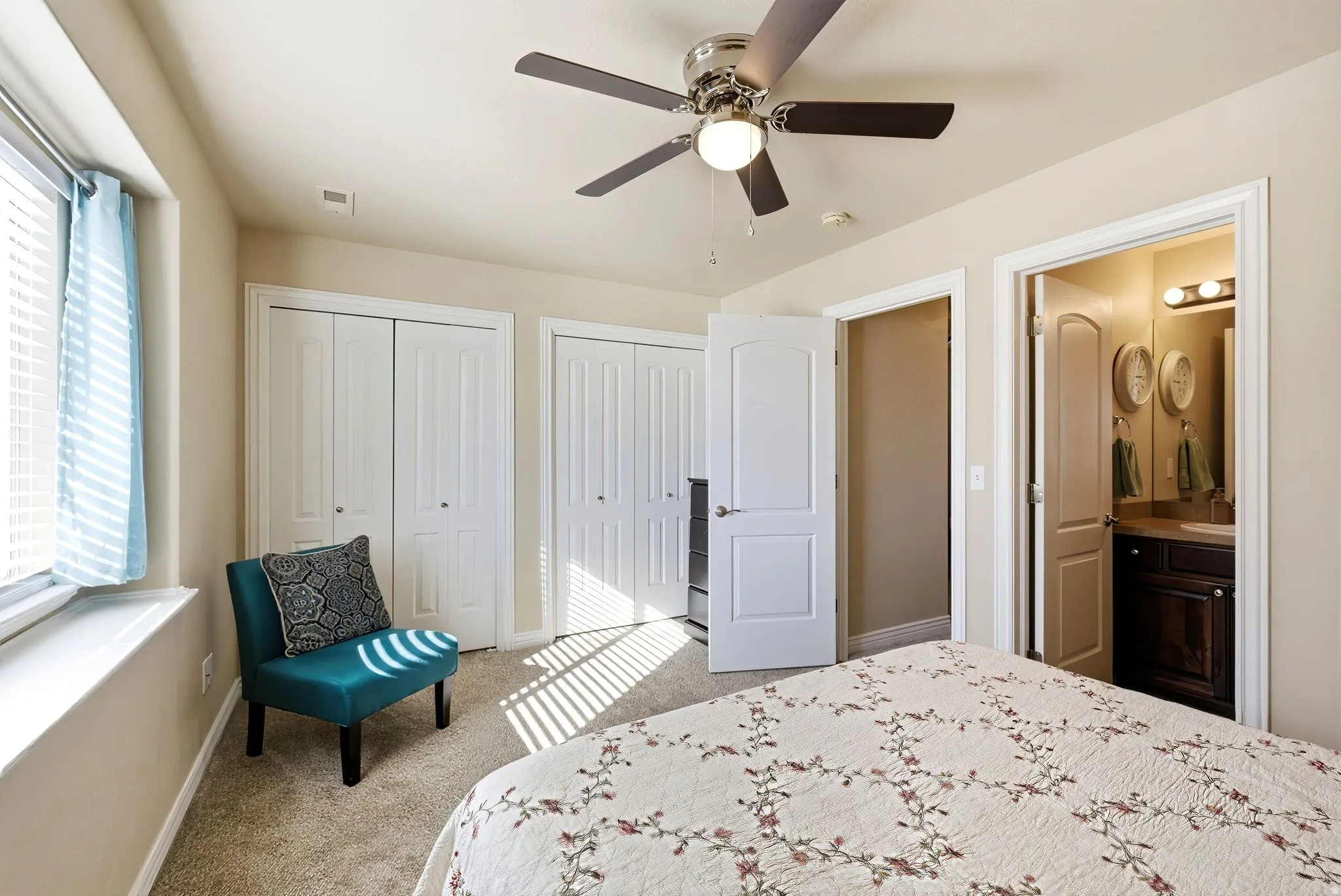 Primary Bedroom with multiple closets, light carpet, a ceiling fan, and connected bathroom
