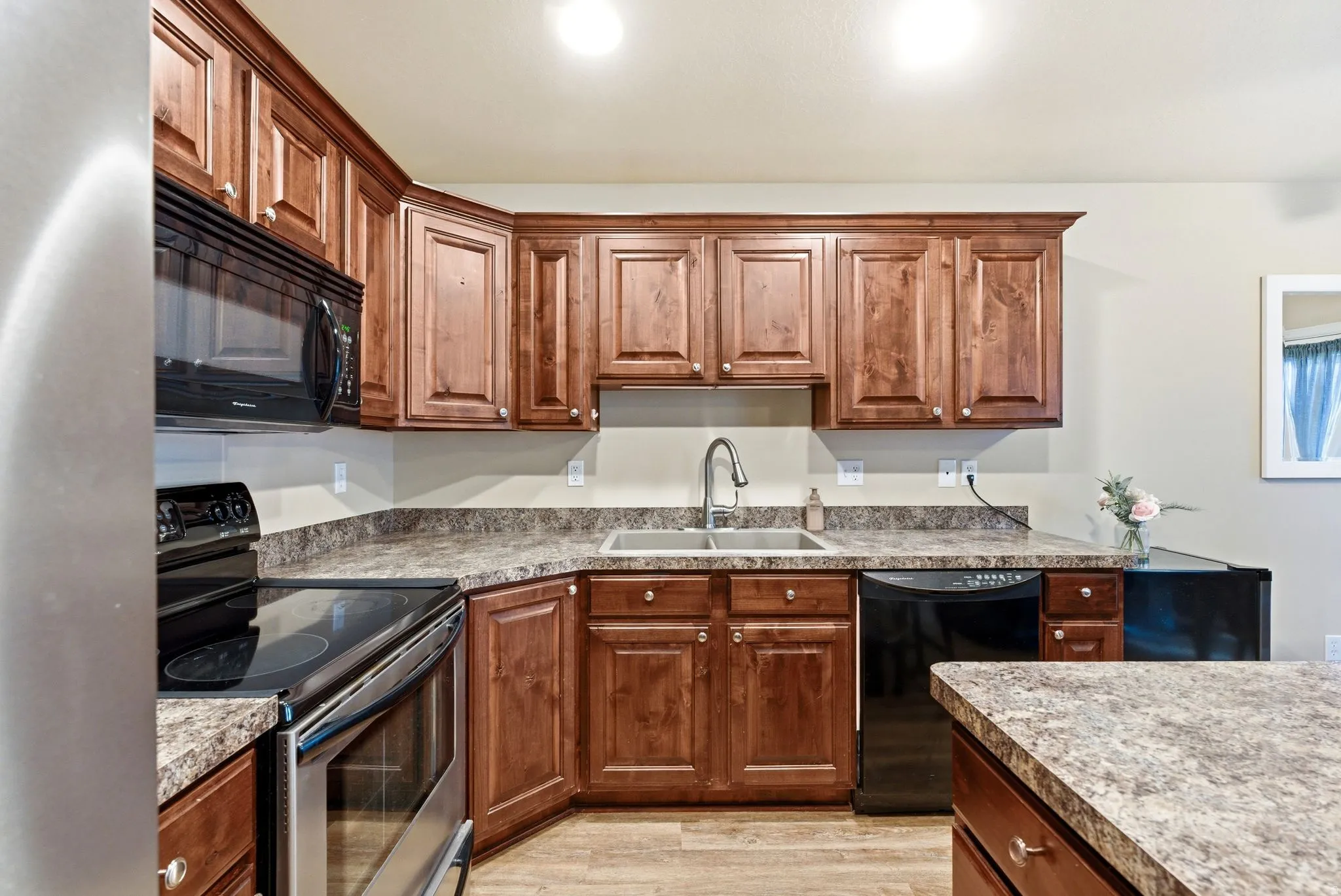 Kitchen featuring black appliances, light wood finished floors, and wood finish cabinetry