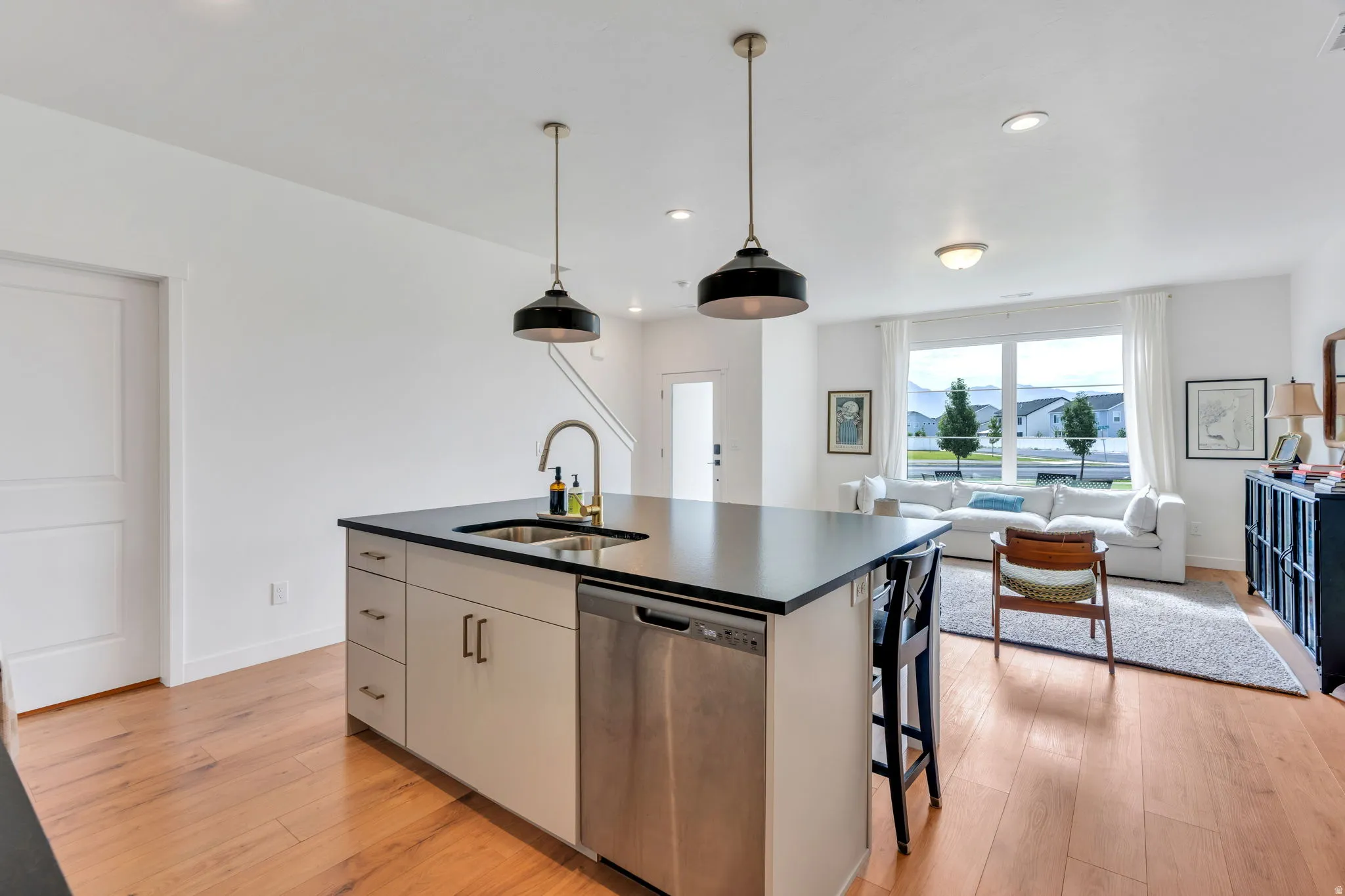 Kitchen island with a dark countertop, undermount sink, and stainless steel dishwasher