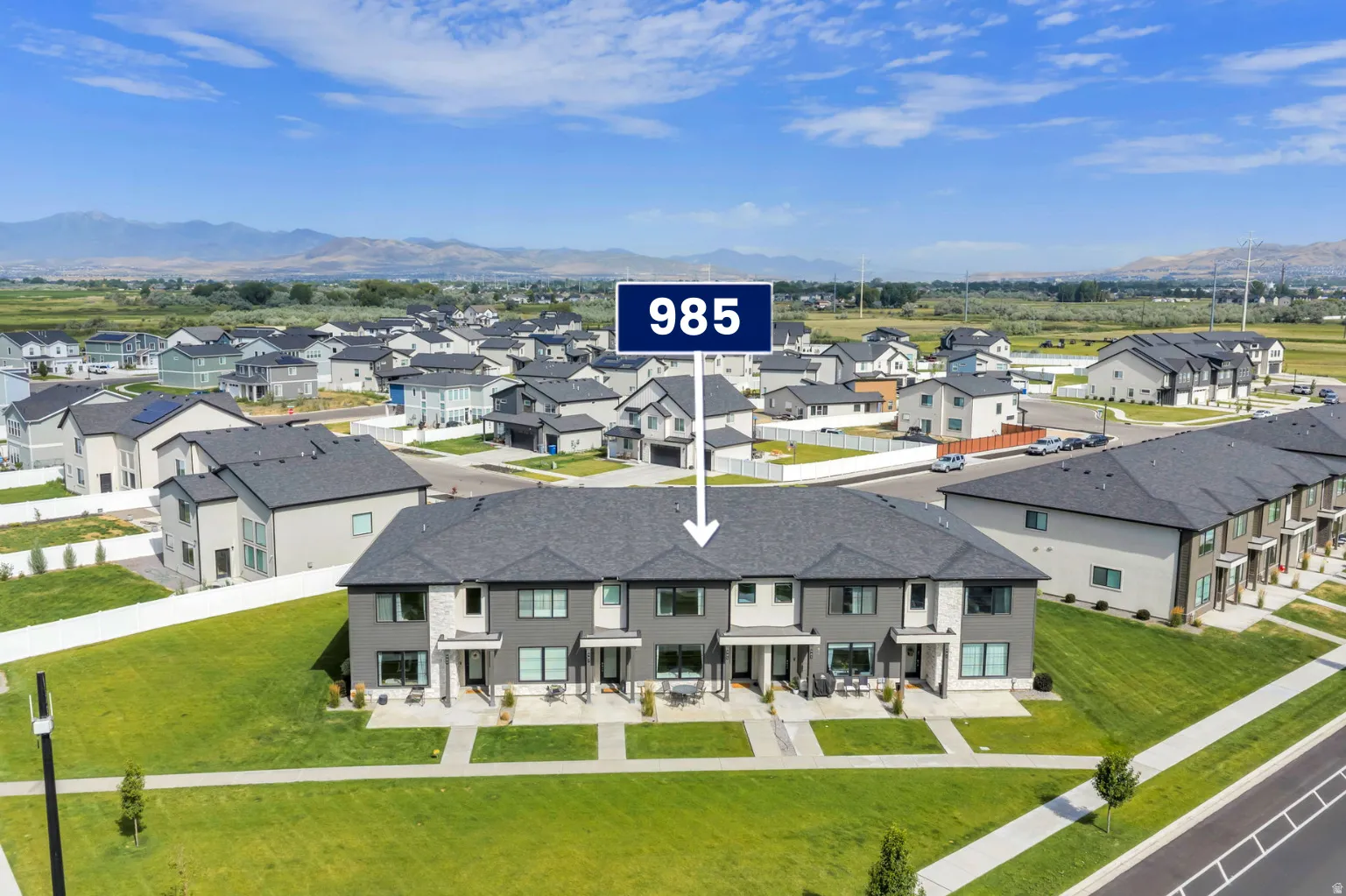 Modern townhome exterior featuring contemporary architecture, dark gray siding, light stone accents, and individual patios