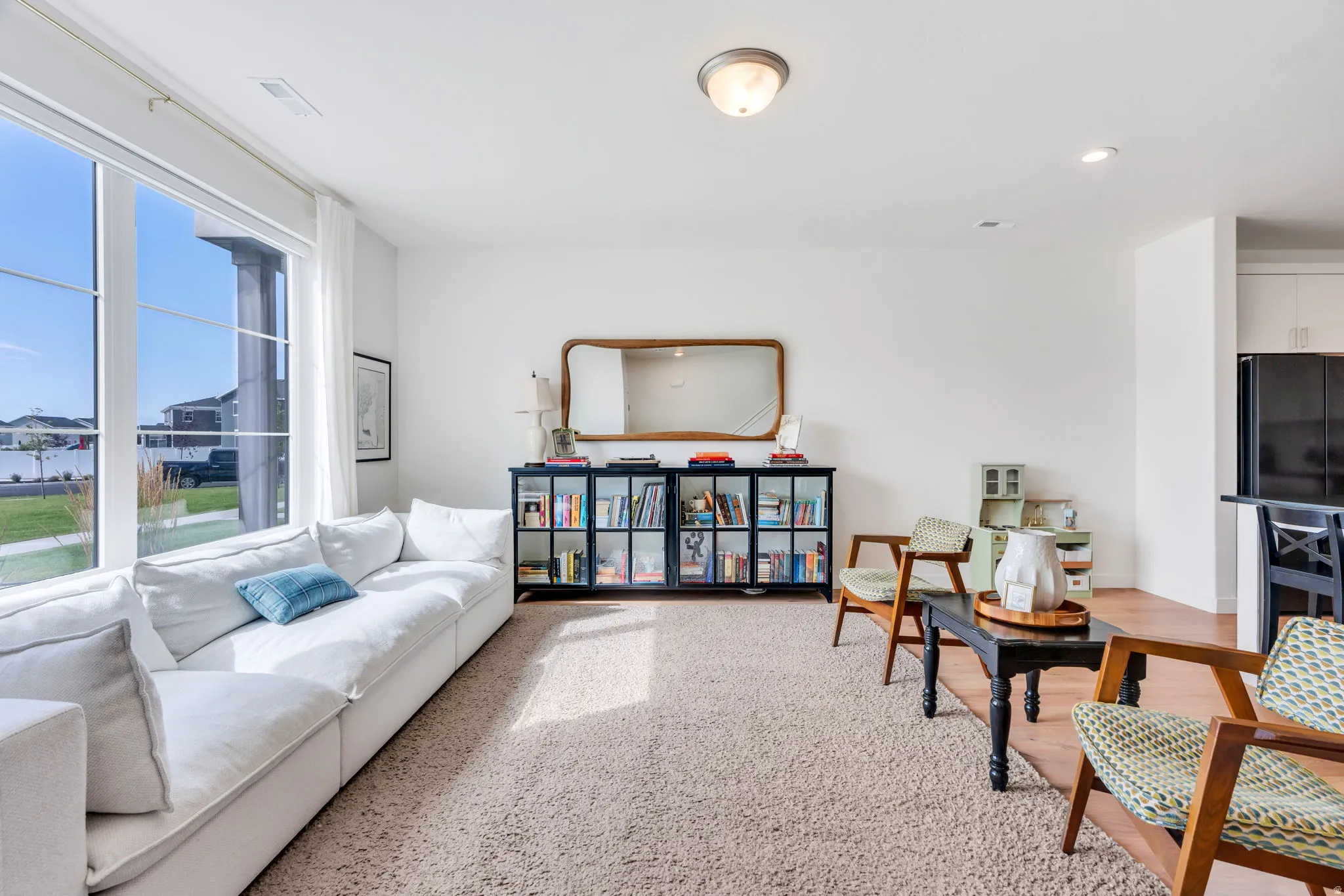 Spacious living area featuring large picture windows, light-toned carpeting, and recessed lighting