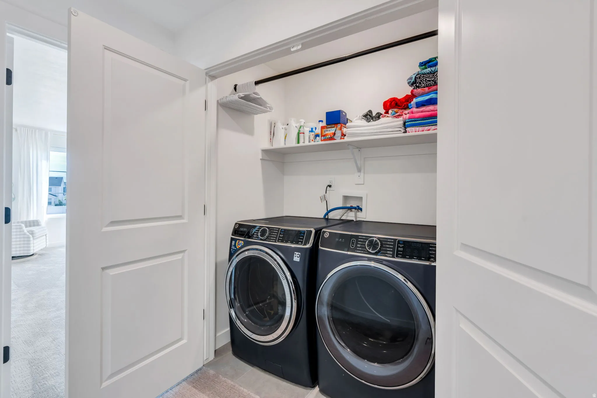 Dedicated laundry closet featuring a built-in shelf, hanging rod, and connections for two appliances
