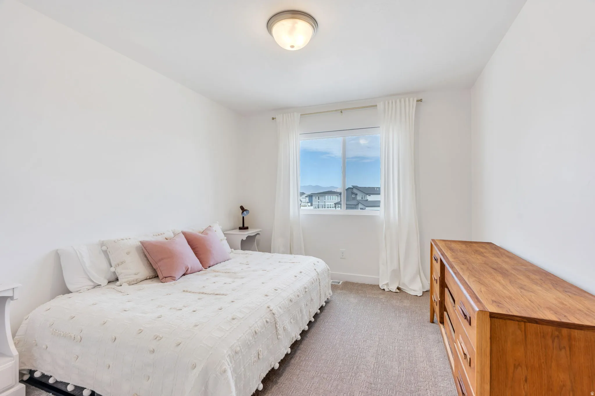 Carpeted interior room featuring a window with natural light, white walls, and a flush mount ceiling light fixture