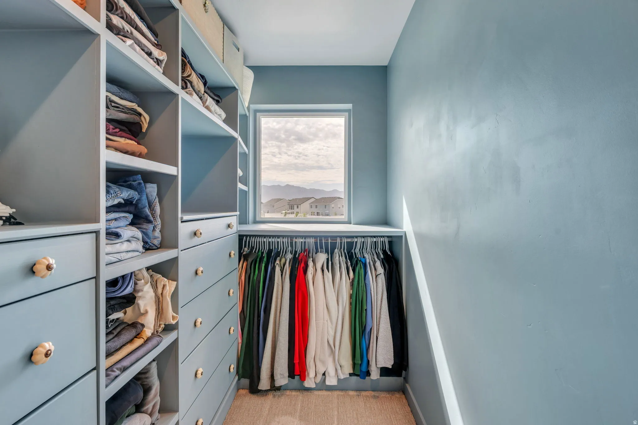 Custom built-in closet system exclusive to this townhome, featuring multiple shelves, drawers with decorative knobs, and hanging rods