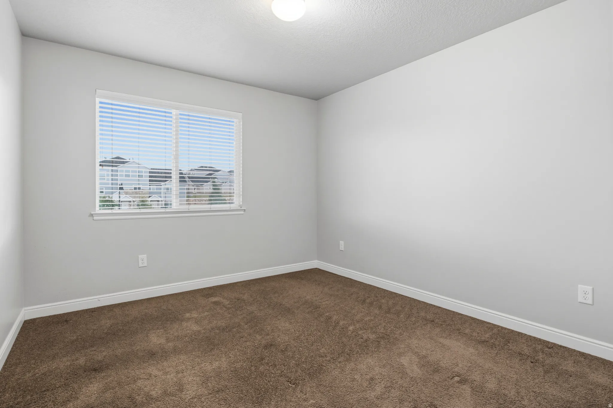 Neutral gray walls and a single window with horizontal blinds create a bright interior space