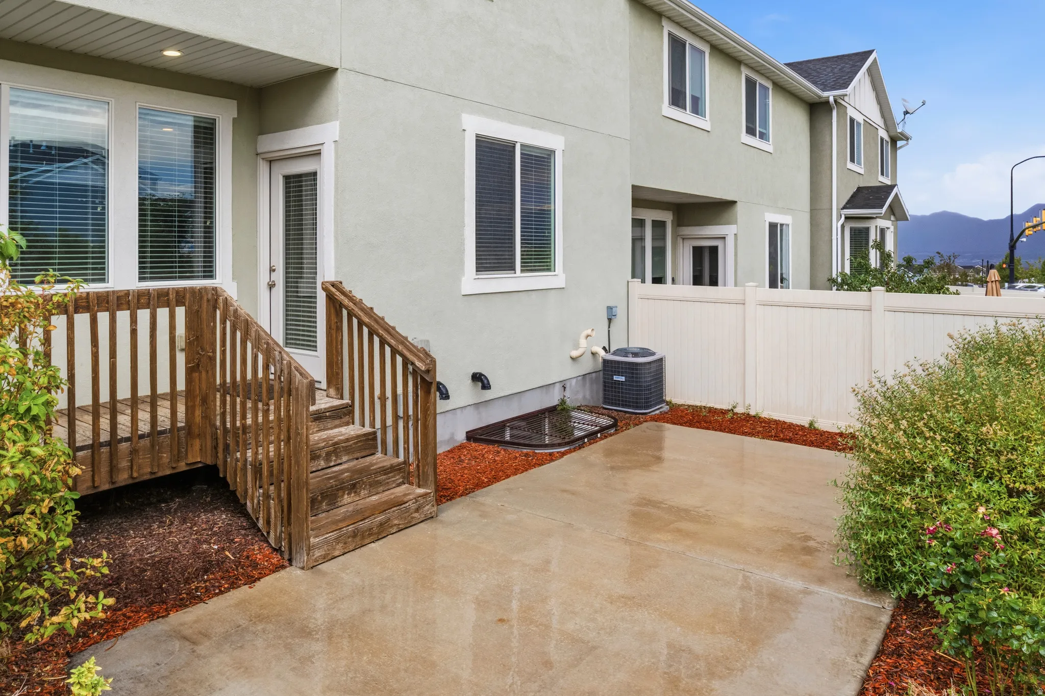 Private patio featuring a concrete surface, wood deck, and white vinyl fencing