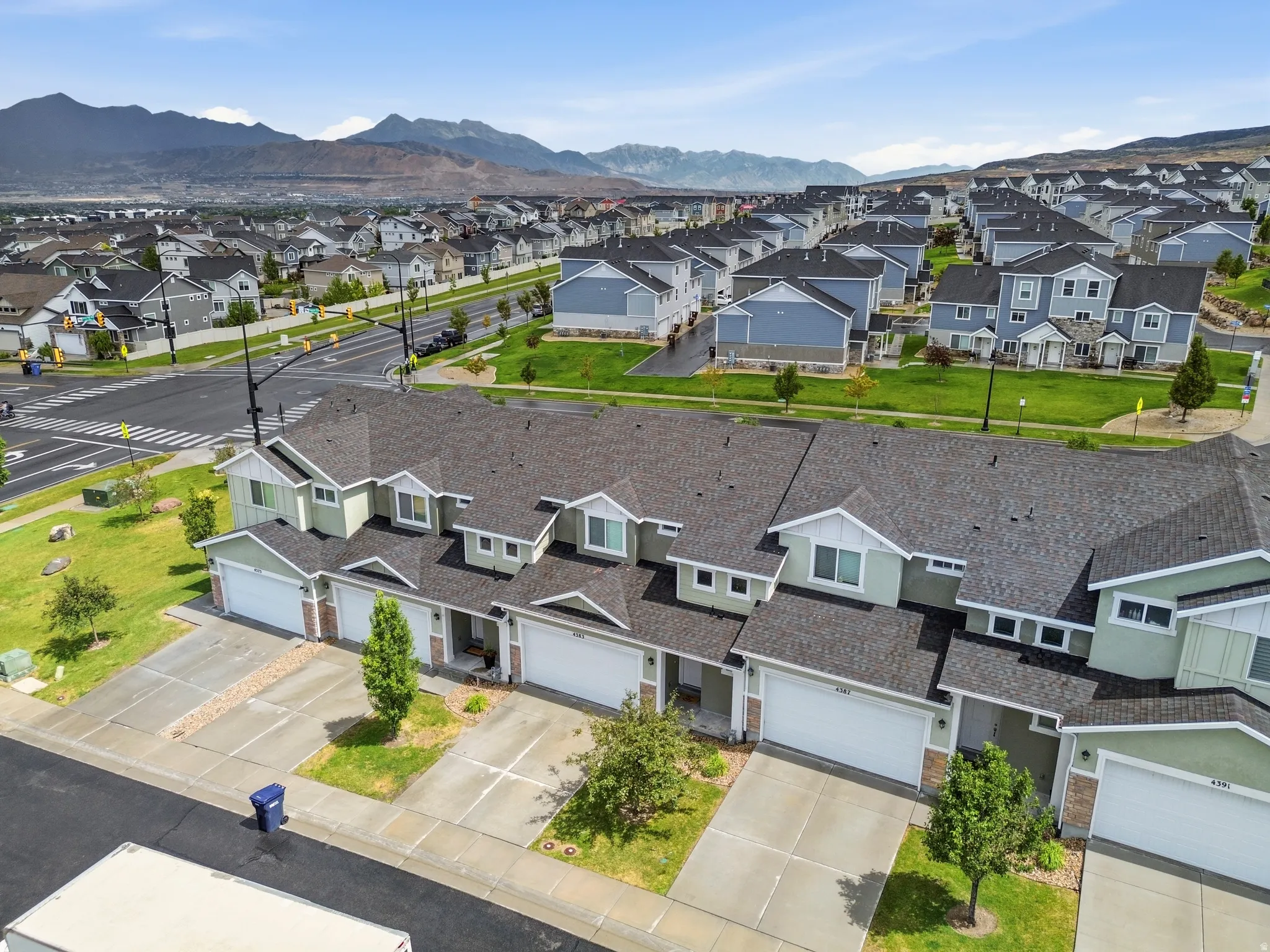 Ariel perspective of a residential community featuring townhomes with attached garages, individual driveways, and manicured landscaping