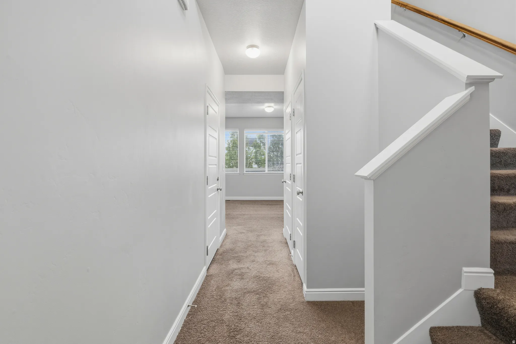 Hallway featuring light gray walls, built-in storage closets, and recessed lighting