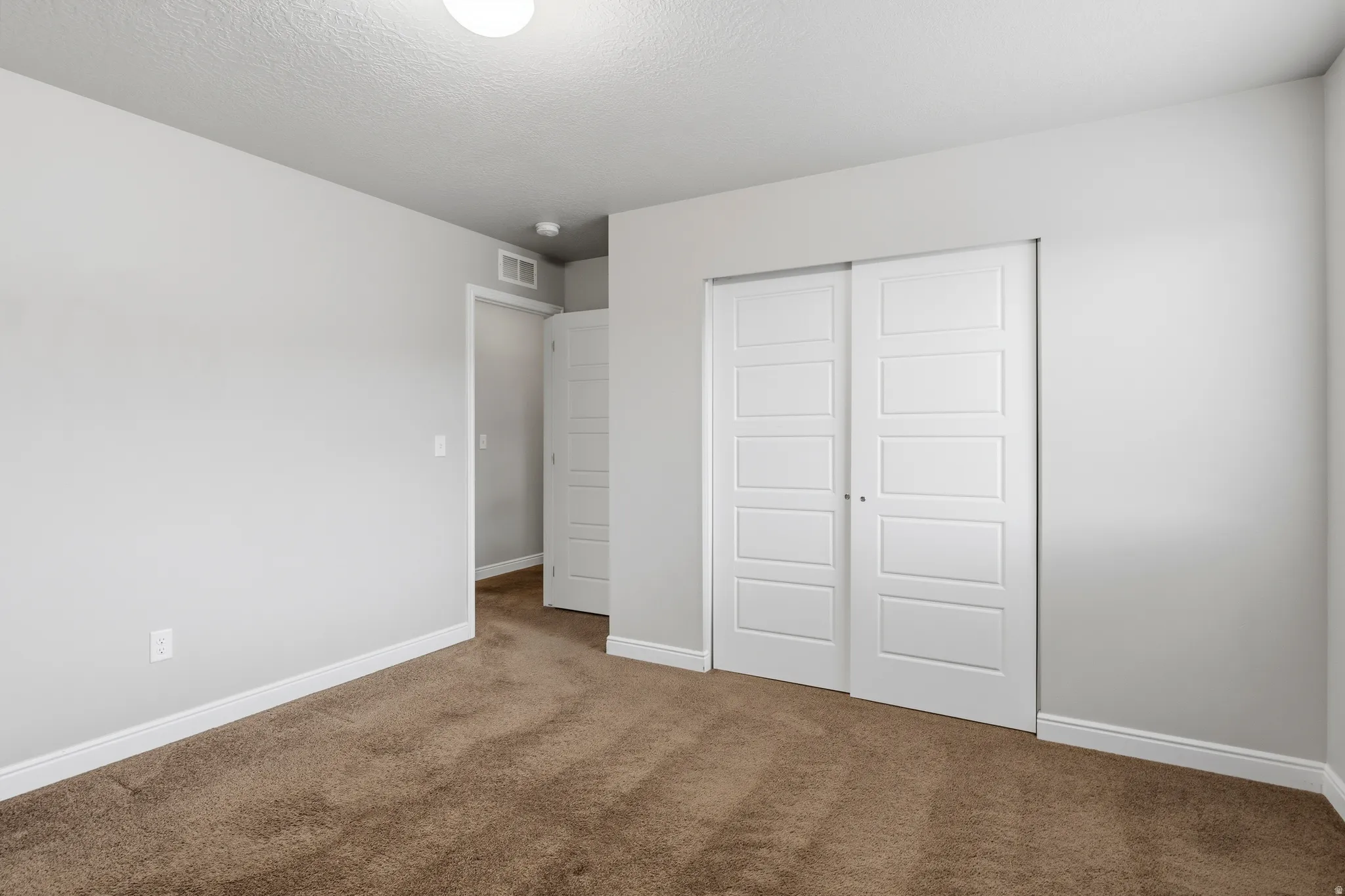 Neutral-toned room featuring light gray walls and brown carpeting