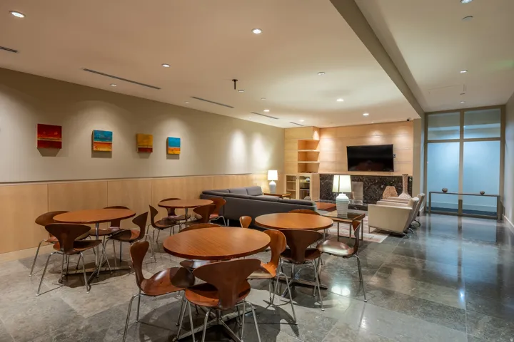 Stone tile flooring throughout, wood-paneled wall accents, recessed lighting, and a built-in media center with a dark stone fireplace surround