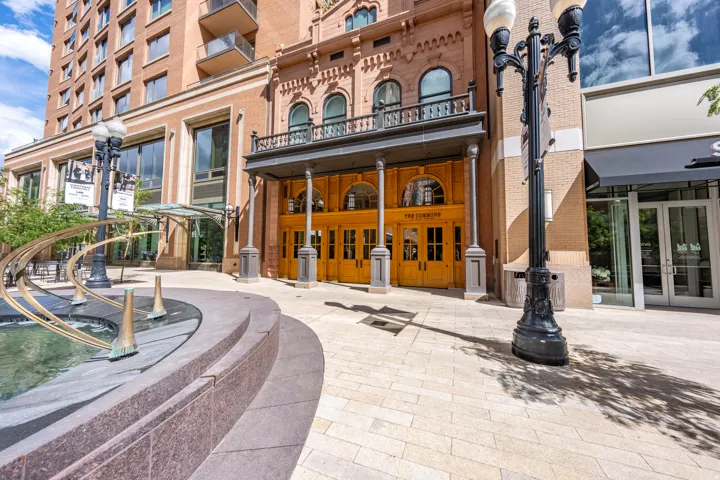 Brick facade building with a grand entrance featuring a balcony, arched windows, and multiple entry doors