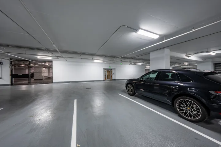 Gated parking garage with overhead lighting and painted concrete flooring