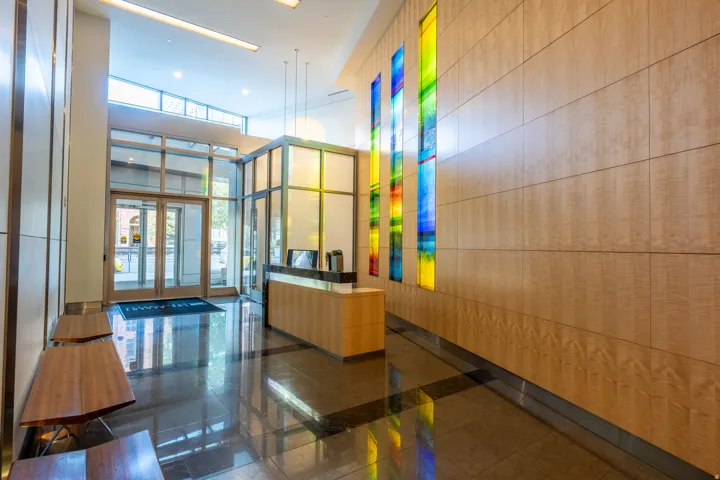 Light wood paneling, polished dark flooring, and a glass-enclosed reception desk with a stone countertop