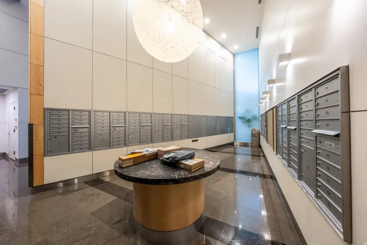 Mailroom area featuring a large spherical pendant light, stone-finish flooring, a round table with a stone top, and multiple wall-mounted mailboxes