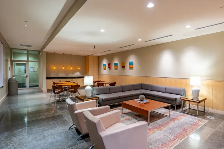 Spacious common area featuring stone flooring, a full-height glass entry door, wood-finish wall paneling, and an integrated built-in serving area with a countertop