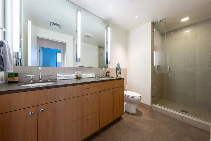 Dual vanity with wood-finish cabinetry, countertop, and integrated sinks